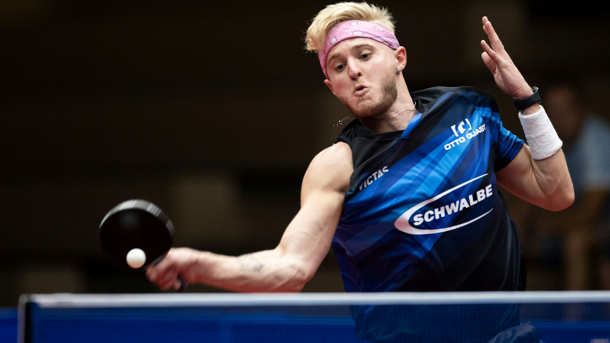 Zu sehen ist ein junger Tischtennisspieler, der den Ball mit der Vorhand über das Netz schlägt.