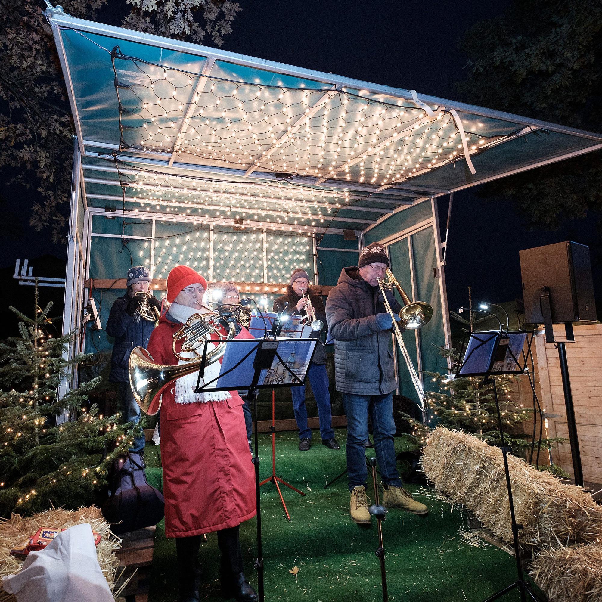 Warm eingepackt lässt der Posaunenchor der evangelischen Kirche Meckenheim seine Instrumente auf der mit Lichterketten und Strohballen geschmückten Bühne erklingen.