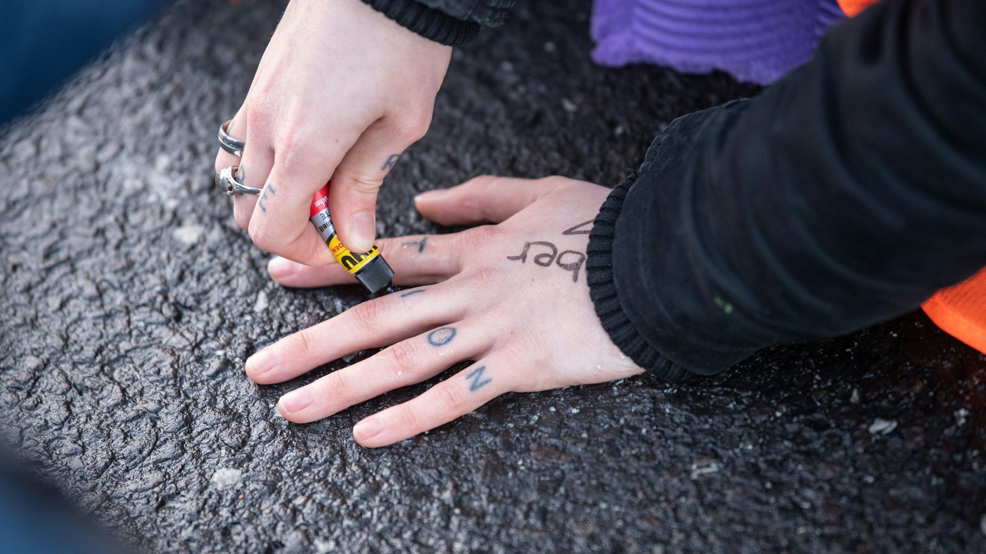 Ein Klimaaktivist der Bewegung „Letzte Generation“ klebt seine Hand auf den Asphalt, um den Verkehr zu blockieren.