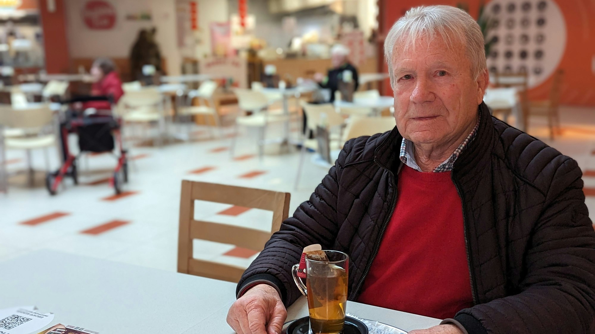 Leo. Fuß sitzt mit einem Tee auf einem Tablett an einem Tisch in einem Restaurant.