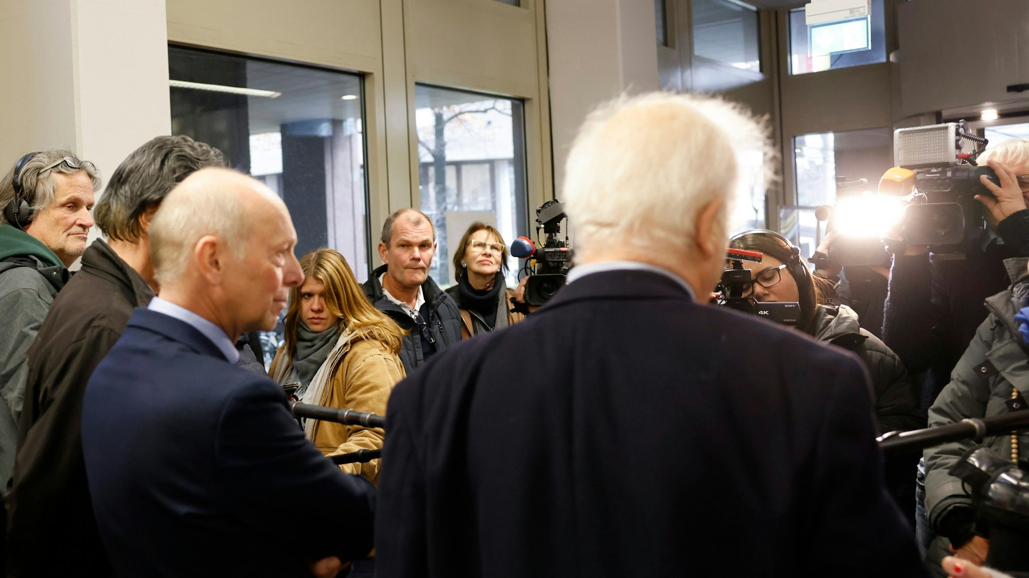 Kläger Georg Menne (M l) steht mit einem seiner Anwälte nach der Verhandlung im Landgericht Köln und beantwortet der Presse Fragen