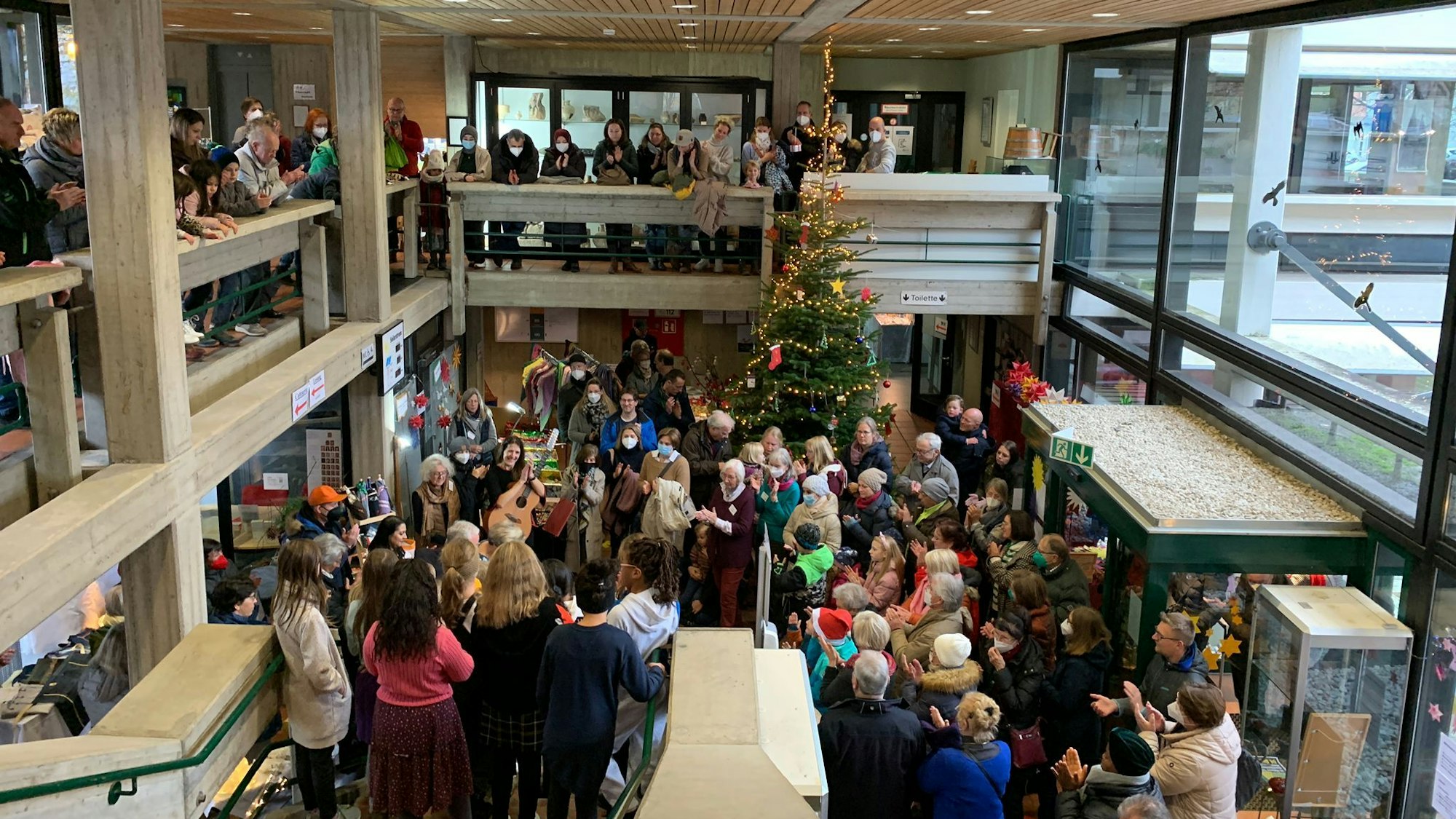 Menschen umringten dicht gedrängt einige Musiker in der Eingangshalle des Alfterer Rathauses. Einige schauen von der Empore zu.