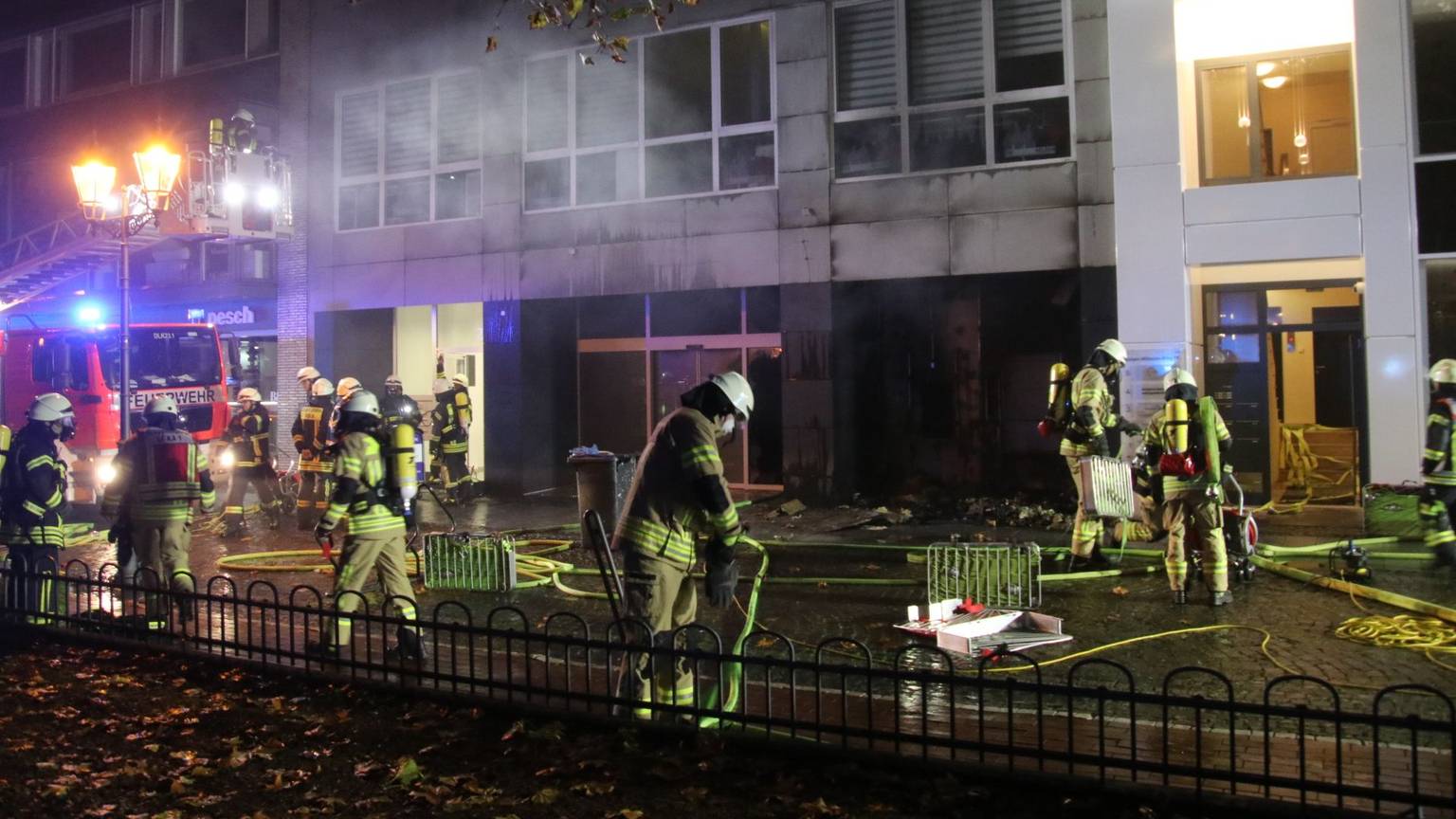 Feuerwehrleute löschen einen Brand am Kaiser-Wilhelm-Ring 20 in Köln. Im Hintergrund ist ein Einsatzfahrzeug zu sehen.