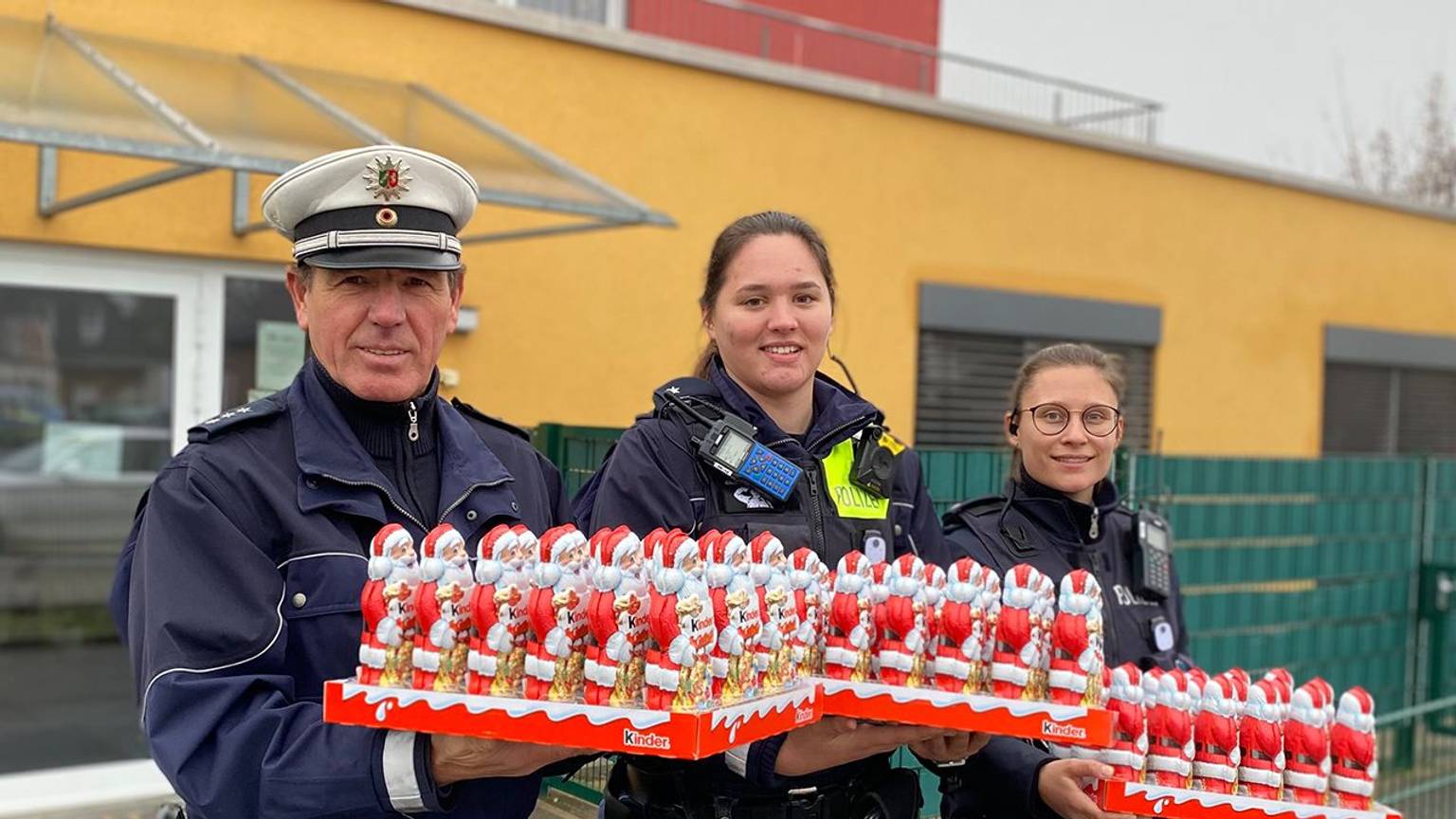 Der Bezirksdienstbeamten aus Sankt Augustin und zwei weitere Polizistinnen halten drei Paletten mit Schokonikoläusen in der Hand.