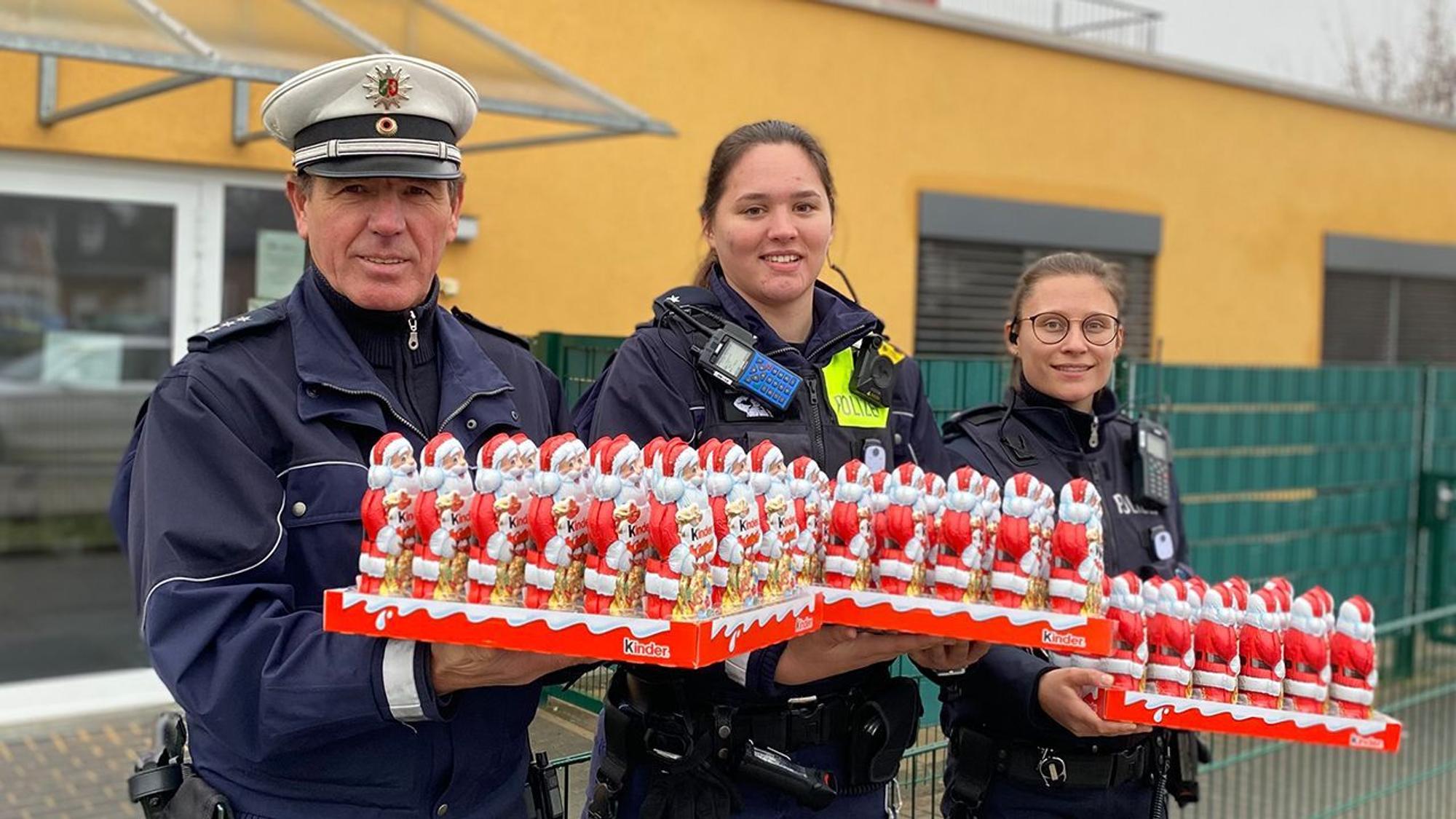 Der Bezirksdienstbeamten aus Sankt Augustin und zwei weitere Polizistinnen halten drei Paletten mit Schokonikoläusen in der Hand.