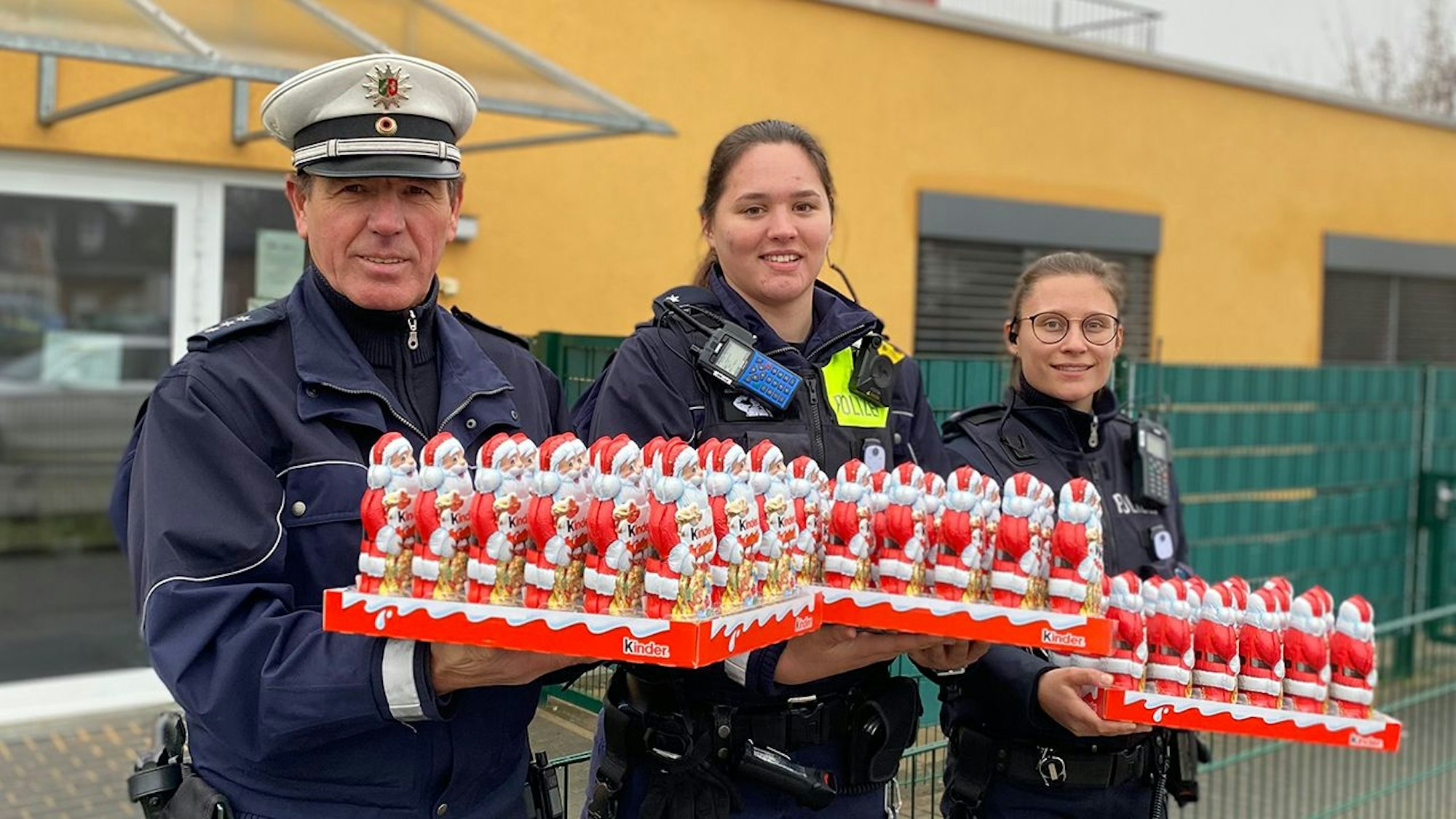 Der Bezirksdienstbeamten aus Sankt Augustin und zwei weitere Polizistinnen halten drei Paletten mit Schokonikoläusen in der Hand.