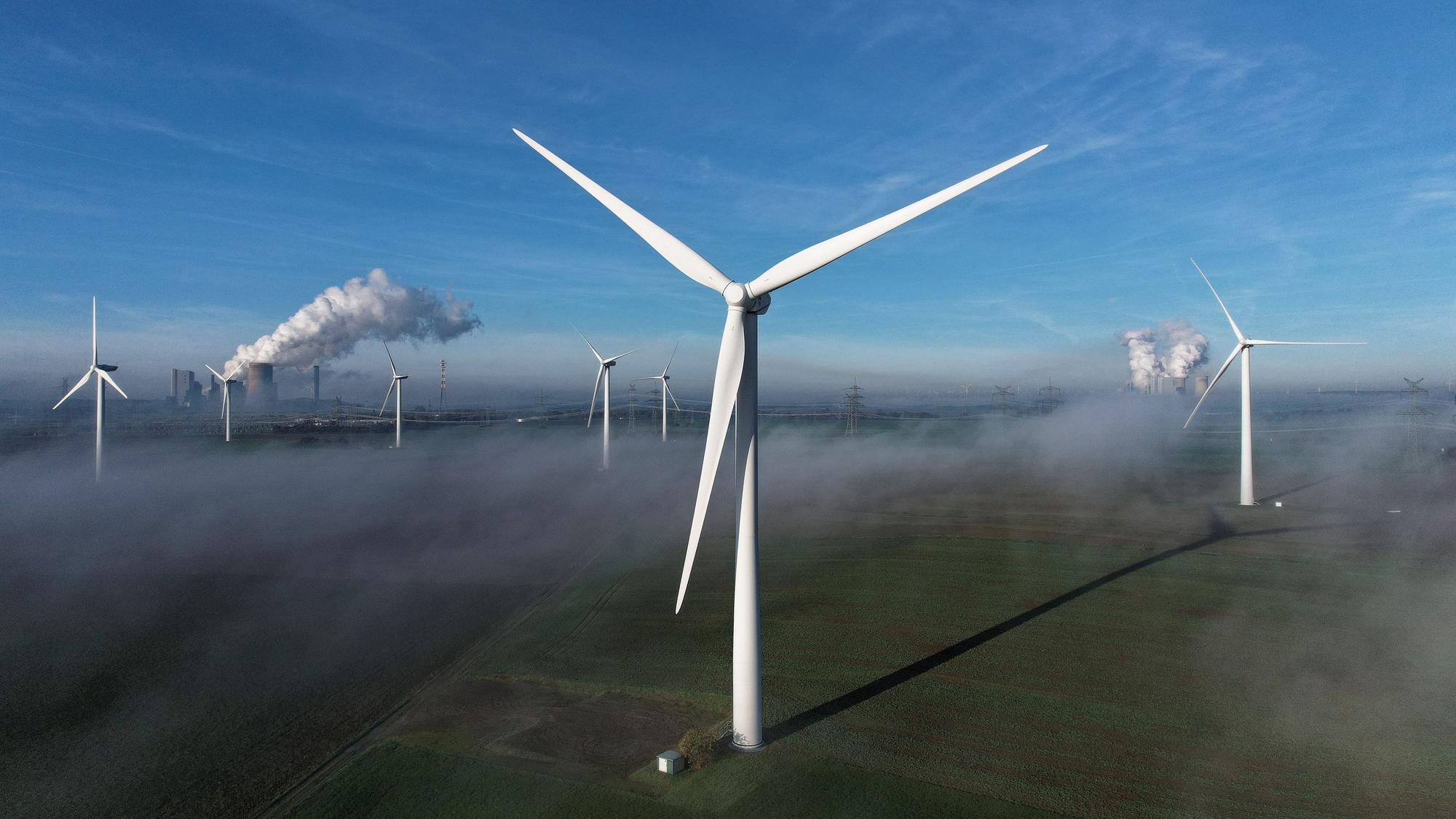 Bergheim: Windräder stehen auf einer Anhöhe. Im Hintergrund sind die Braunkohlekraftwerke Niederaußem und Neurath zu sehen.