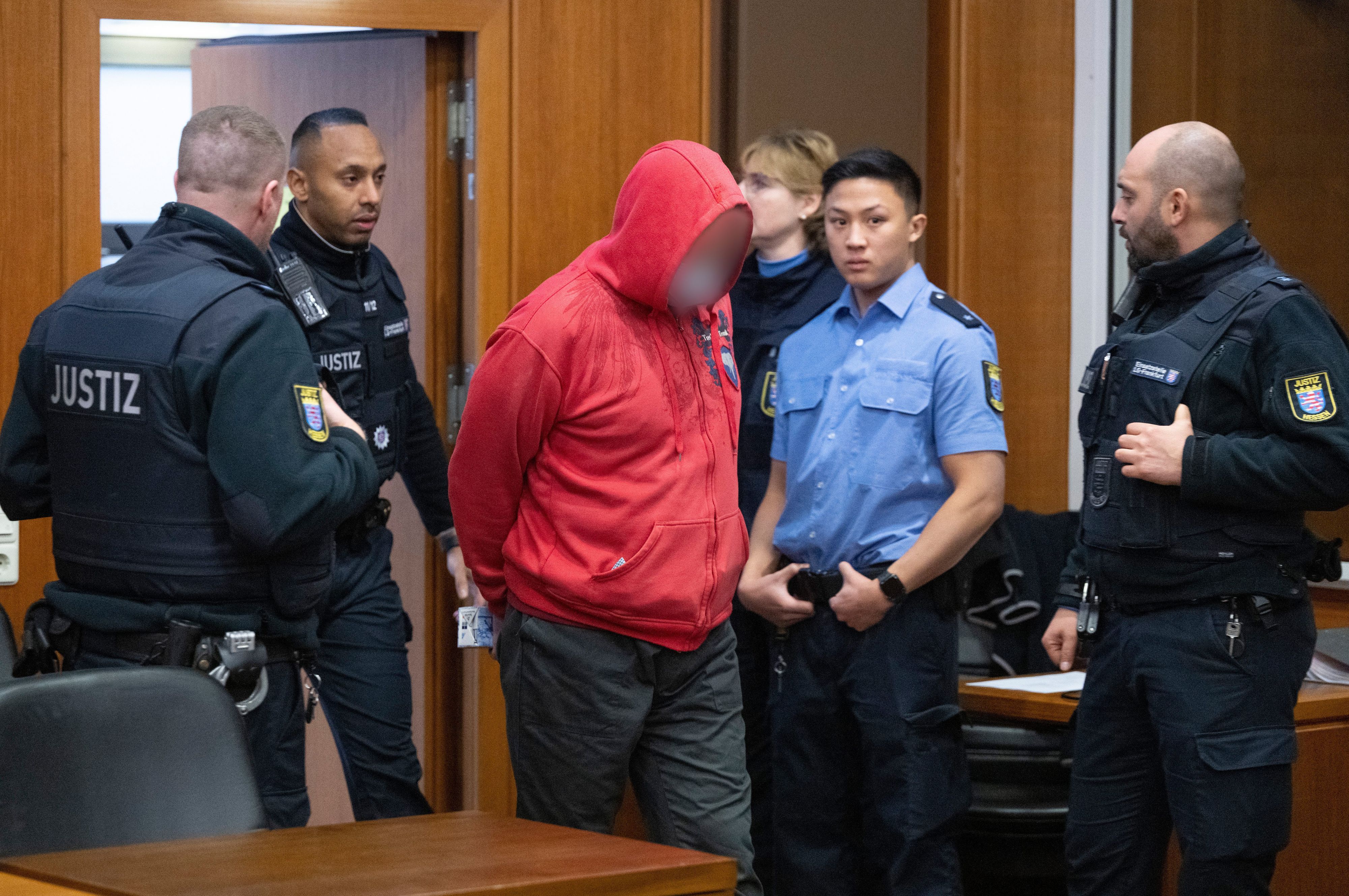 Einer der Angeklagten im „BoysTown“-Prozess wird von einem Justizwachtmeister in den Verhandlungssaal geführt. In dem Verfahren mussten sich vier Männer im Alter von 42 bis 66 Jahren verantworten.