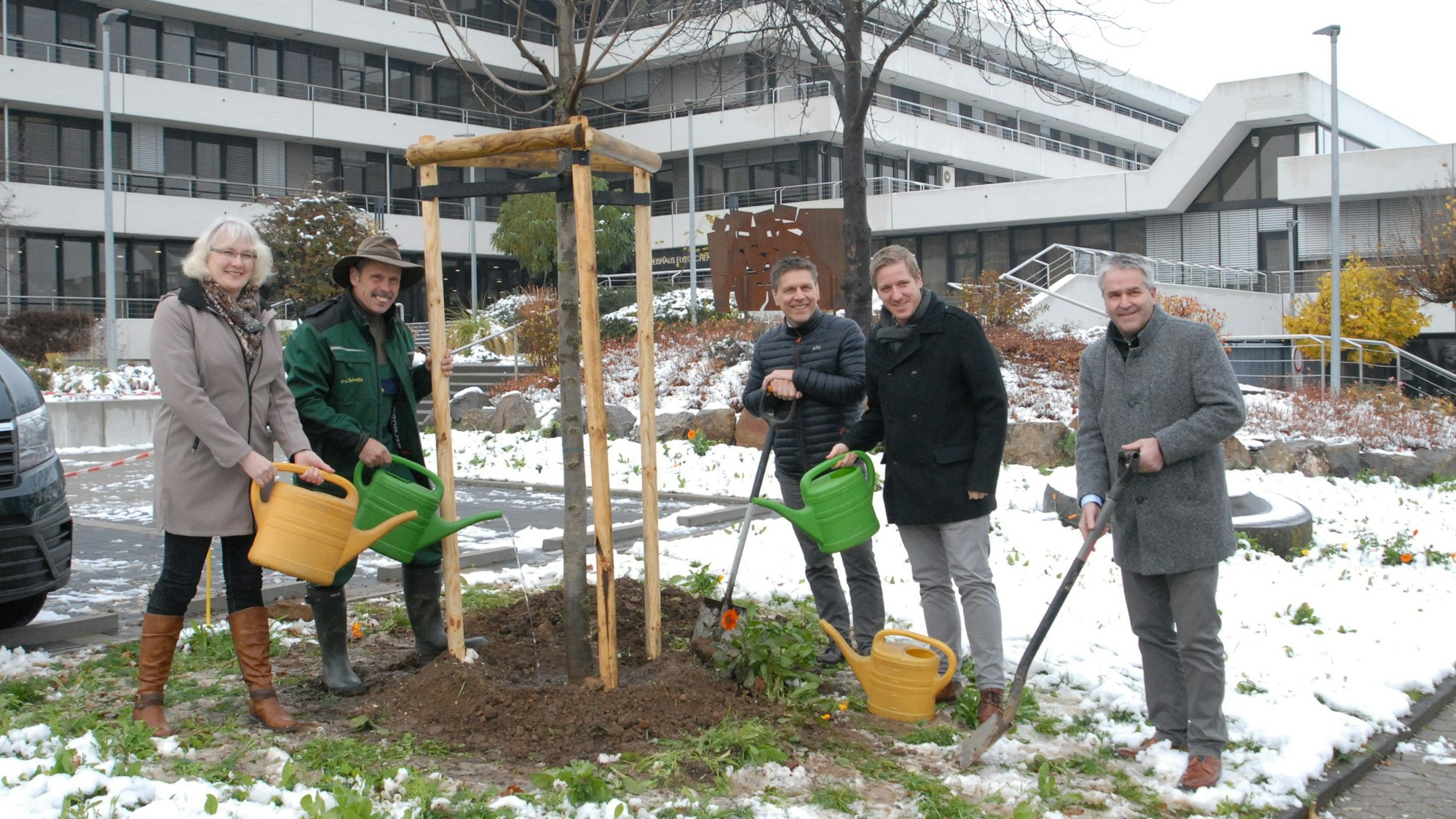 Mit Gießkannen und Spaten stehen Heike Schmitz (v.l.), Karl-Josef Schmitz, Stefan Dott, Markus Ramers und Markus Böhm an dem Baum, den sie gerade gepflanzt haben.