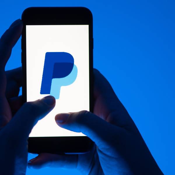 Eine Frau hält ein Smartphone mit dem Logo des Bezahldienst Paypal in der Hand.