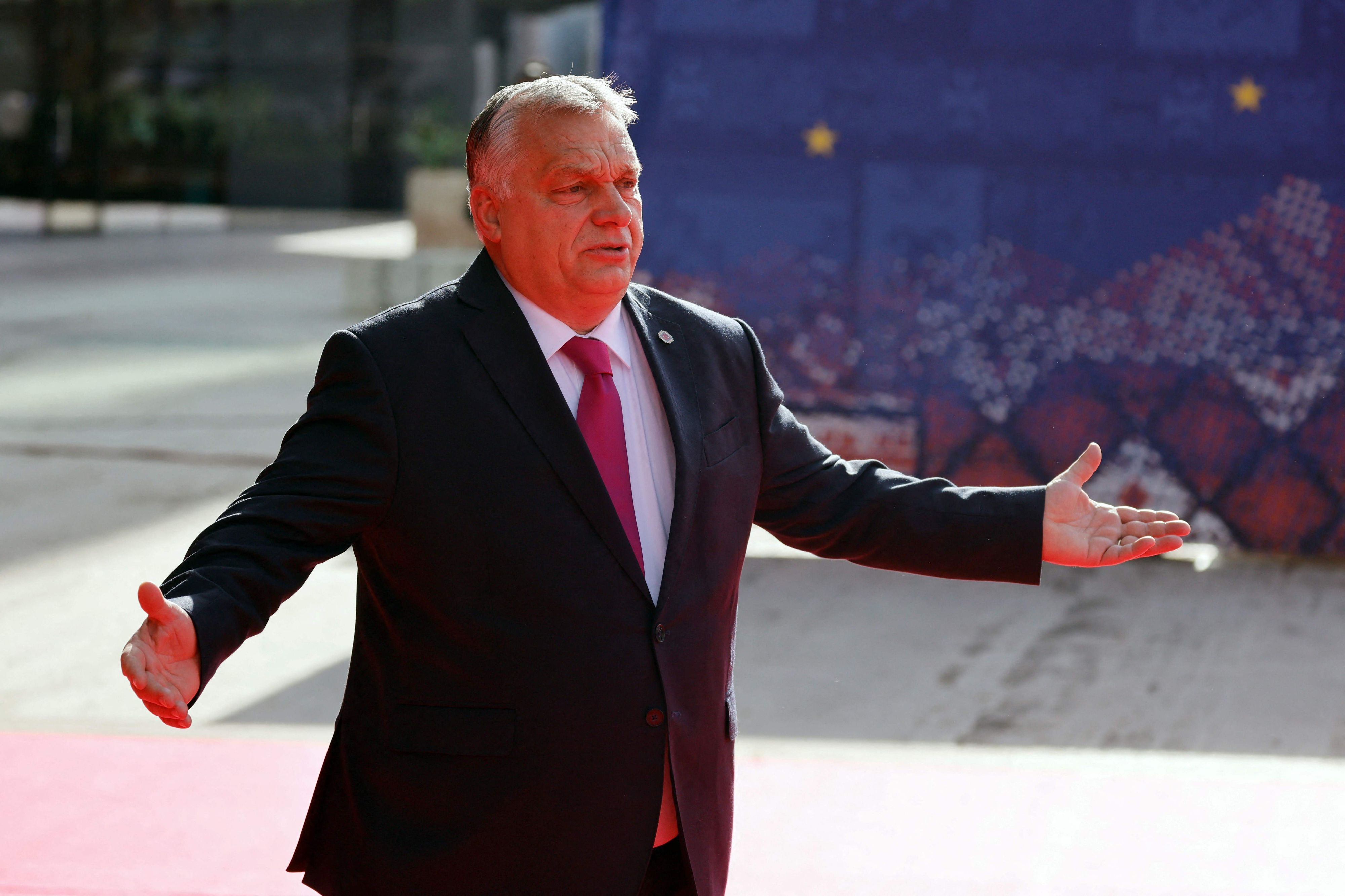 Ungarns Präsident Viktor Orban steht im Anzug bei einem Kongress und breitet die Arme aus.