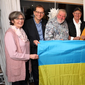 Beteiligte der Ukraine-Hilfe und der Bethe-Stiftung halten eine Ukraine-Flagge vor sich.