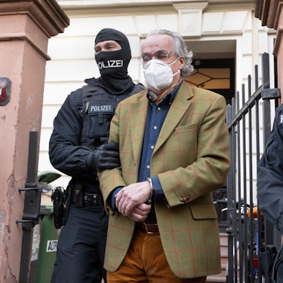 Bei einer Razzia gegen sogenannte „Reichsbürger“ führen vermummte Polizisten nach der Durchsuchung eines Hauses Heinrich XIII Prinz Reuß (M.) zu einem Polizeifahrzeug. Er trägt dabei Handschellen.