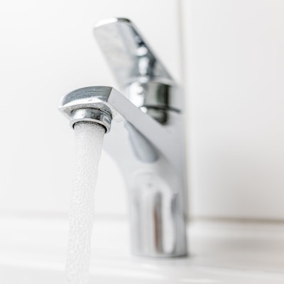 Wasser fließt aus einem Hahn in ein Waschbecken.