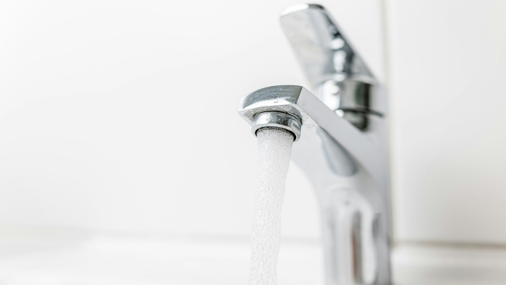 Wasser fließt aus einem Hahn in ein Waschbecken.