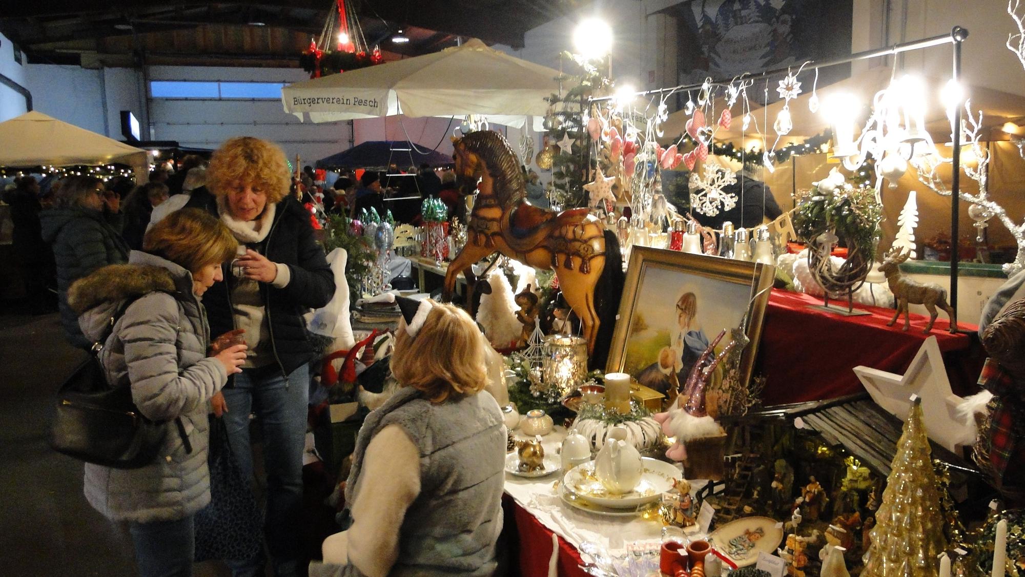 Drei Frauen unterhalten sich in einer Scheune an einem Stand mit Weihnachtsschmuck.
