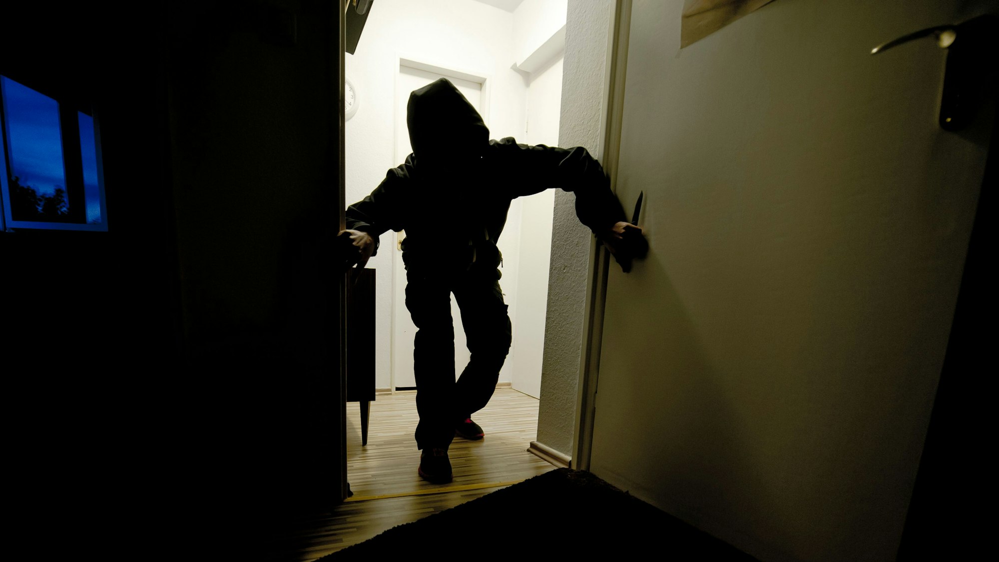 Ein mit einem Messer bewaffneter Mann schleicht durch eine Wohnung. Das Foto wurde gestellt.