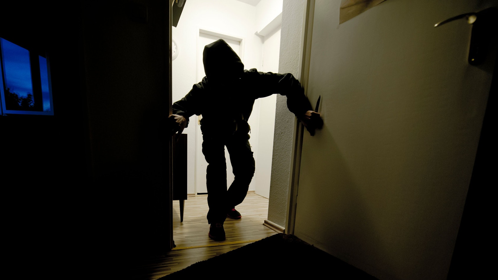 Ein mit einem Messer bewaffneter Mann schleicht durch eine Wohnung. Das Foto wurde gestellt.