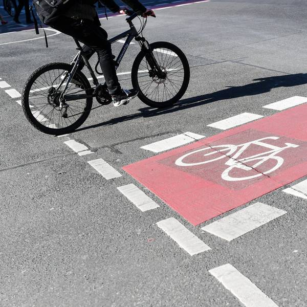 Ein Radfahrer fährt auf einer Straße neben einer rot markierten Radweg.