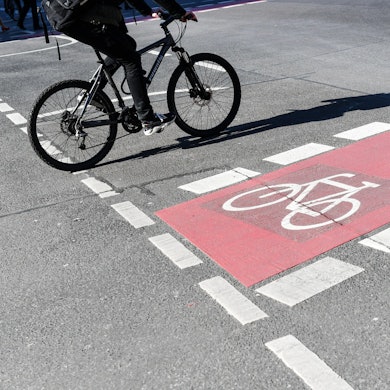 Ein Radfahrer fährt auf einer Straße neben einer rot markierten Radweg.