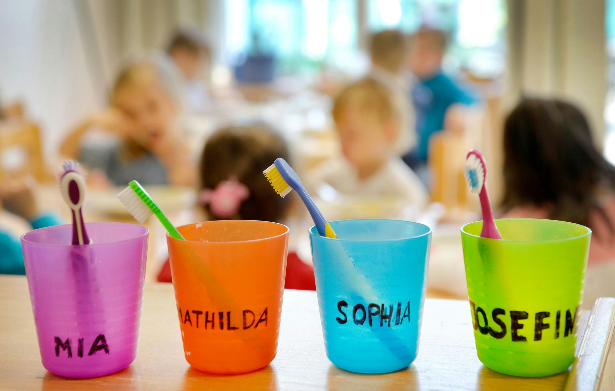 In beschrifteten Bechern stehen Zahnbürsten.