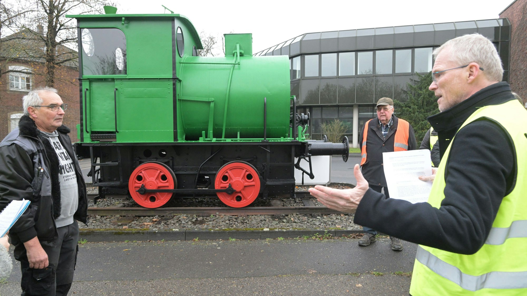 Werner von Rymon (l.) und Bürgermeister Frank Stein stehen vor der grünen, frisch restaurierten Lok. Im Hintergrund ist Karl Hubert Hagen, Vorsitzender des Verschöngerungsvereins zu sehen.