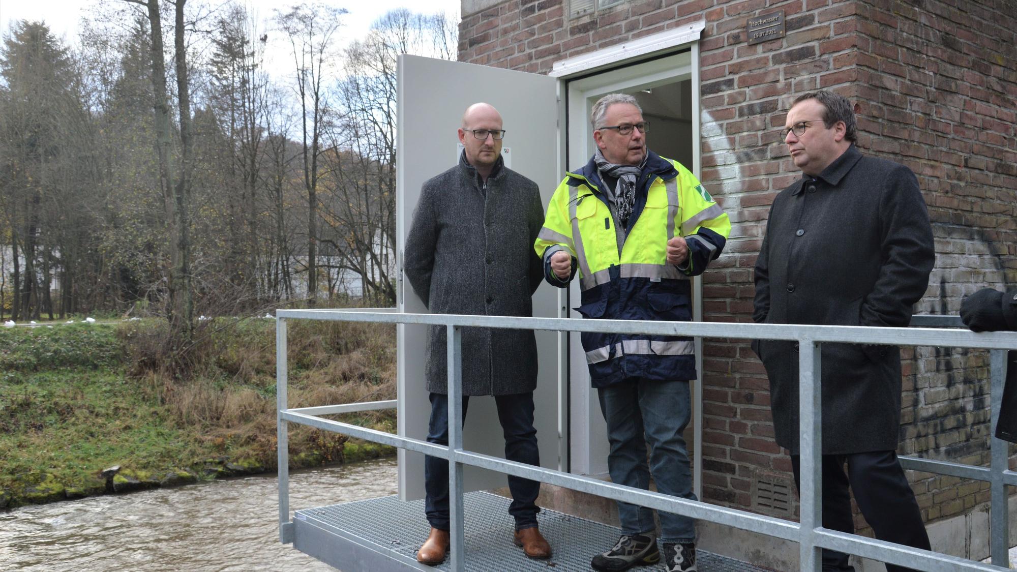 Drei Männer stehen auf einem Metallsteg, der als Zugang für das Pegelhäuschen in Gemünd an der Urft dient.