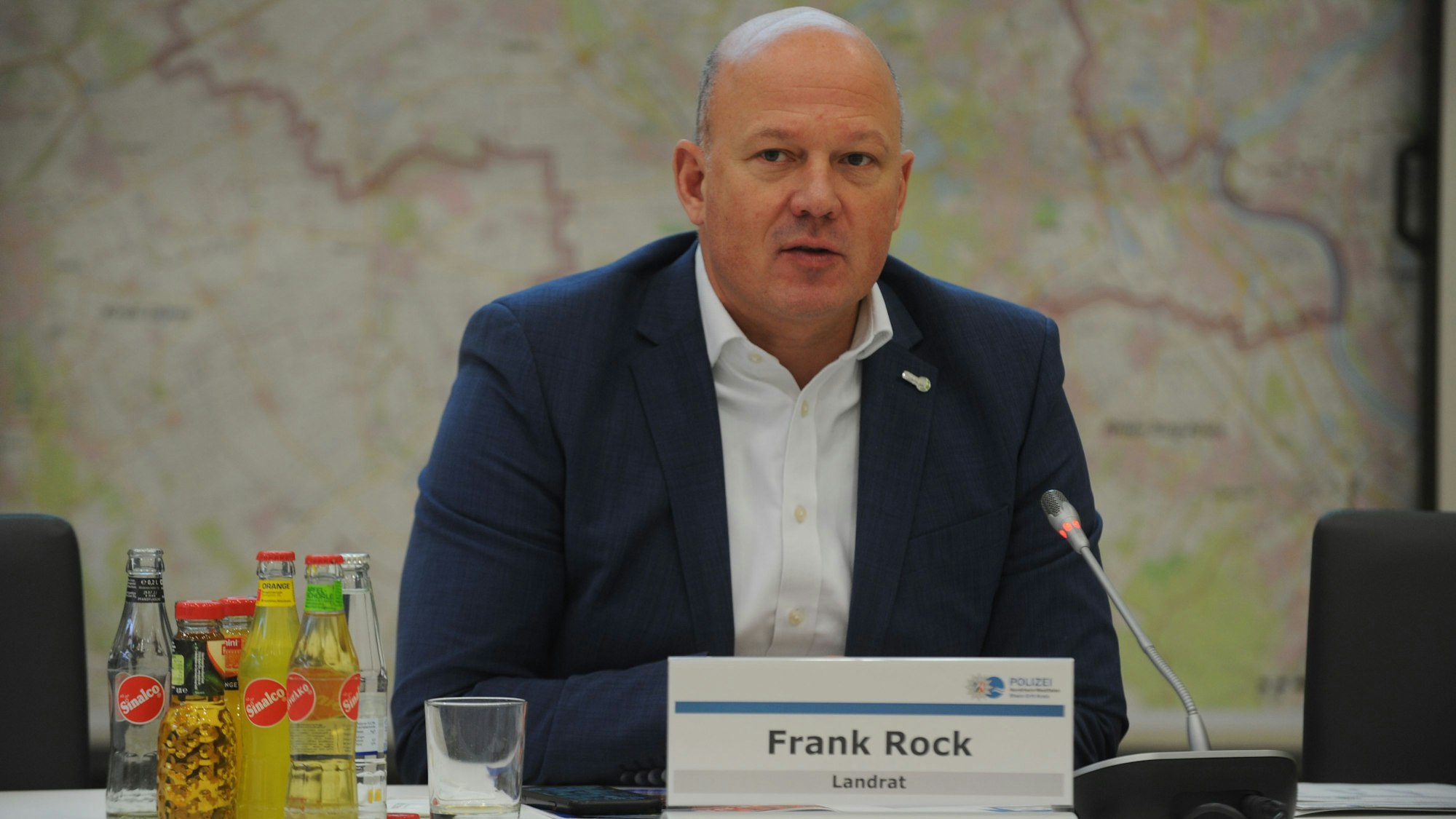 Auf dem Foto ist Landrat Frank Rock zu sehen. Er spricht bei einer Pressekonferenz in ein Mikrofon.
