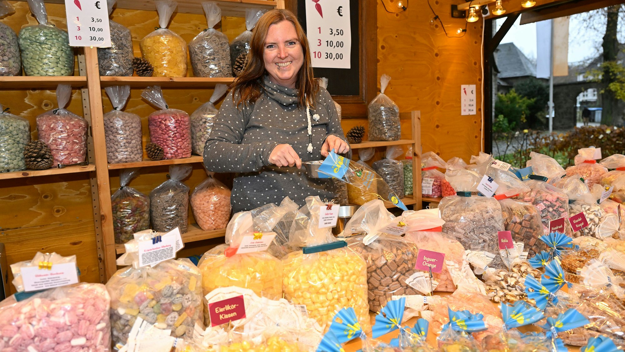 Ellen Schwarz, Martbeschickerin in Bergisch Gladbach, steht in ihrem Stand vor vielen bunten Tütchen, die mit Süßigkeiten gefüllt sind.