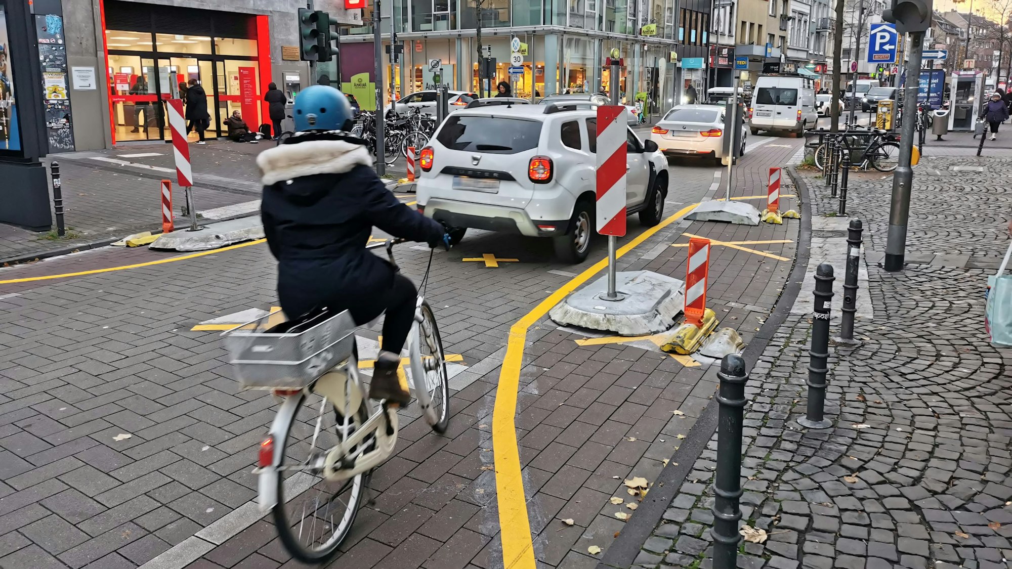 Eine Radfahrerin fährt auf der Venloer Straße hinter mehreren Autos durch eine Engstelle.