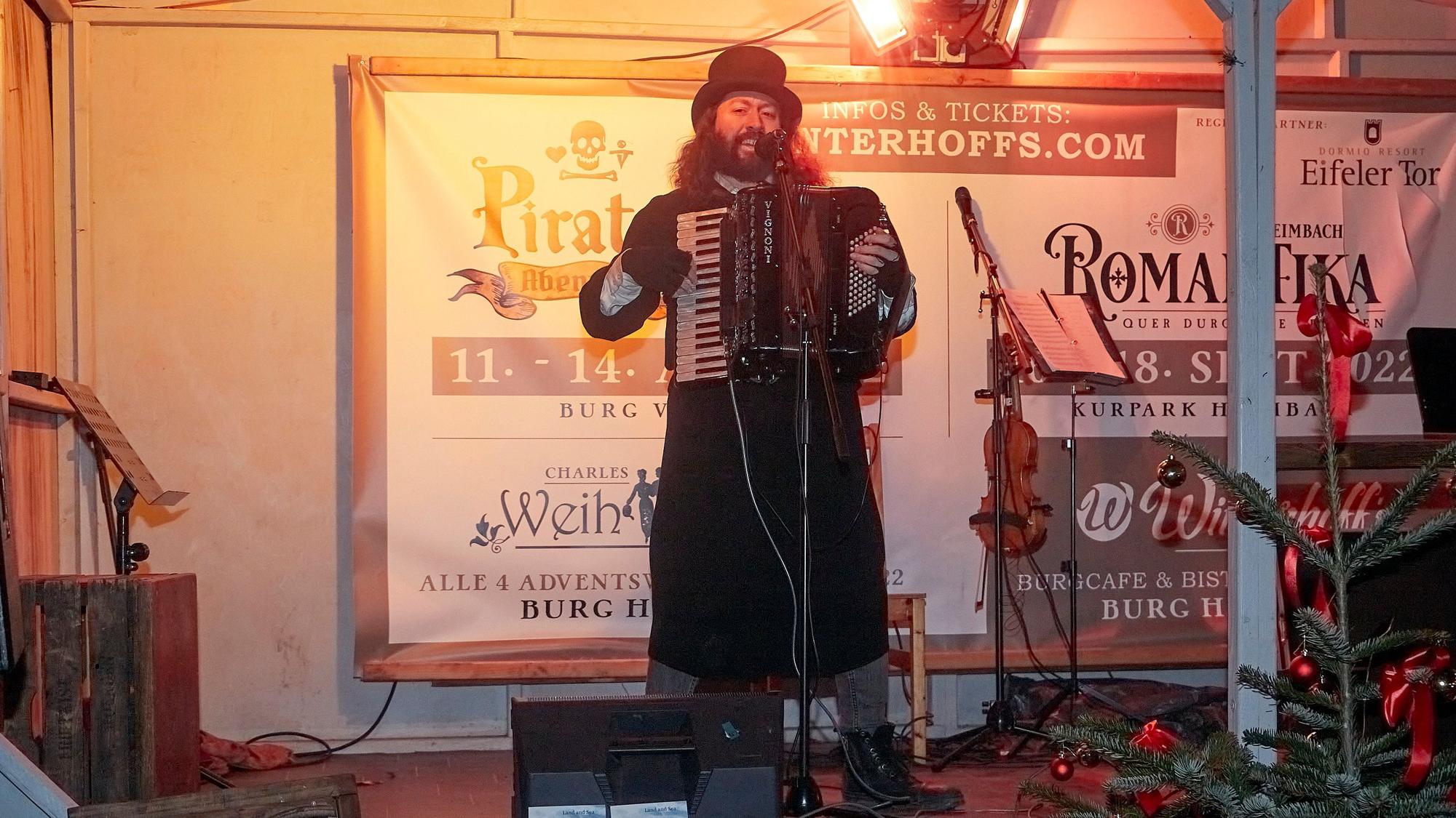 Der Folksänger Felix Clement, stilvoll mit Gehrock und Zylinder gekleidet, spielt auf einem Akkordeon irische, schottische und englische Weihnachtslieder.