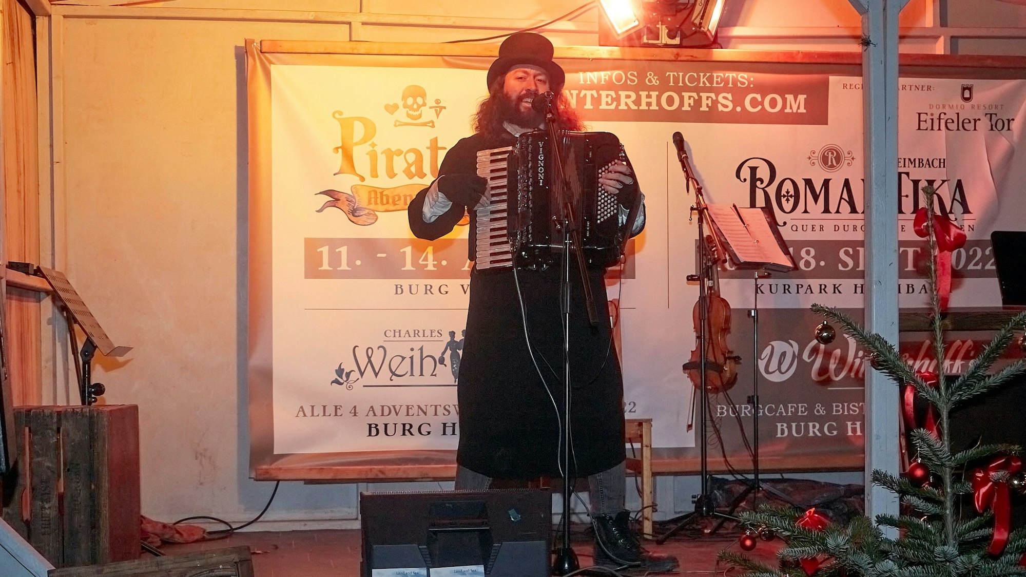Der Folksänger Felix Clement, stilvoll mit Gehrock und Zylinder gekleidet, spielt auf einem Akkordeon irische, schottische und englische Weihnachtslieder.