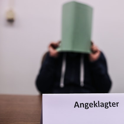 Köln: Der Angeklagte im Missbrauchskomplex Wermelskirchen hält sich im Gerichtssaal eine Mappe vor das Gesicht.