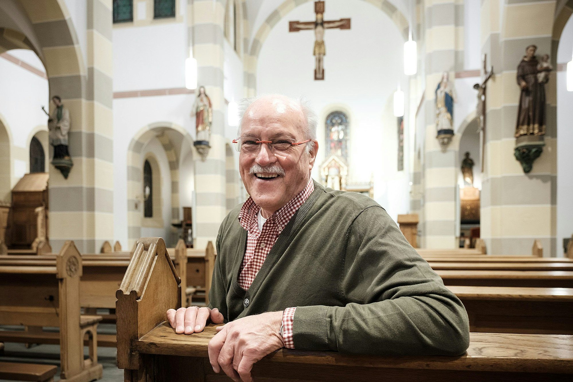 St. Martinus Ollheim: Heiner Meurs sitzt fröhlich im renovierten Innenraum der Kirche.