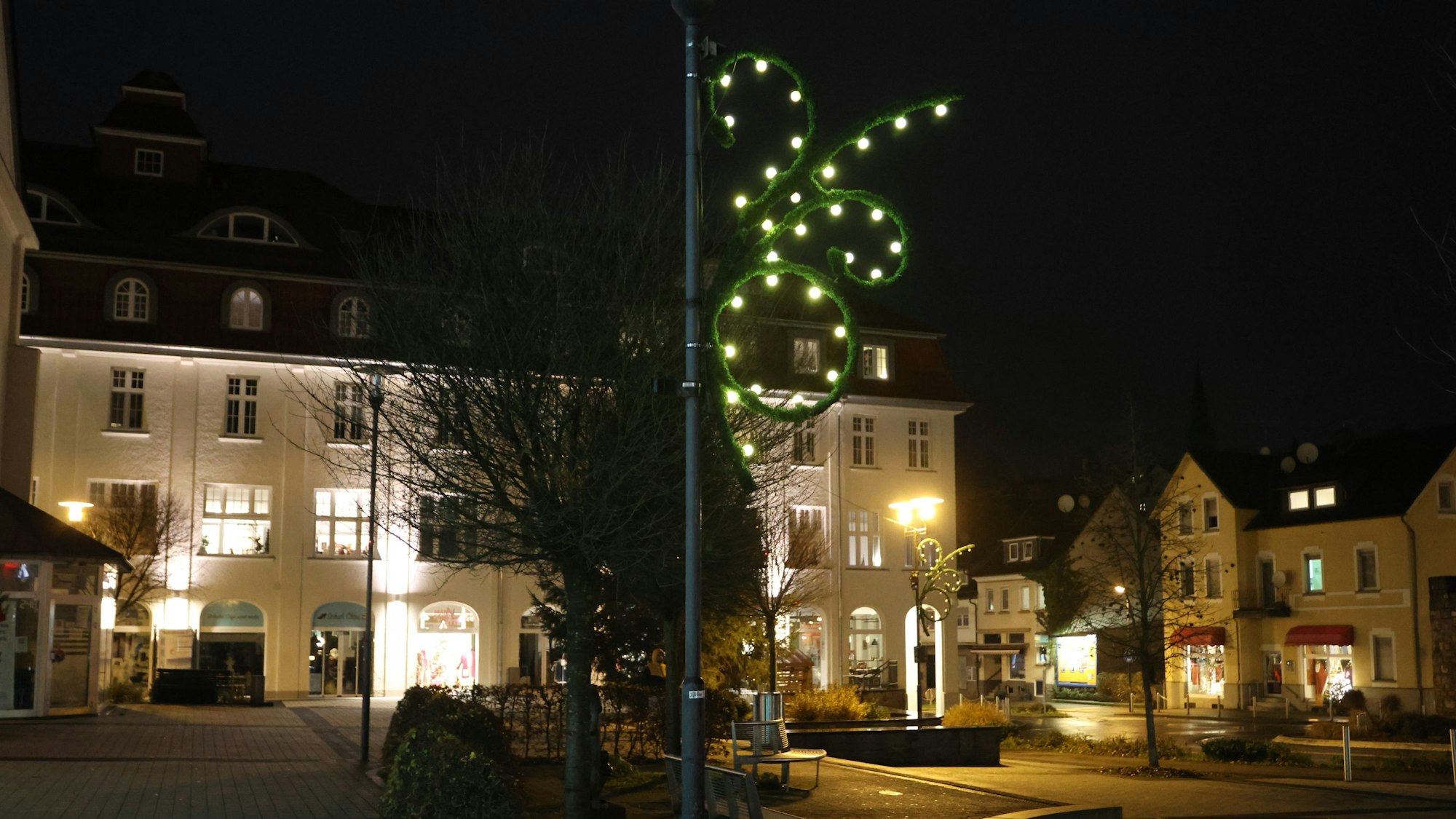 Auf dem dunklen Rathausplatz in Bergneustadt leuchtet eine Lichterkette an einem Laternenmast.
