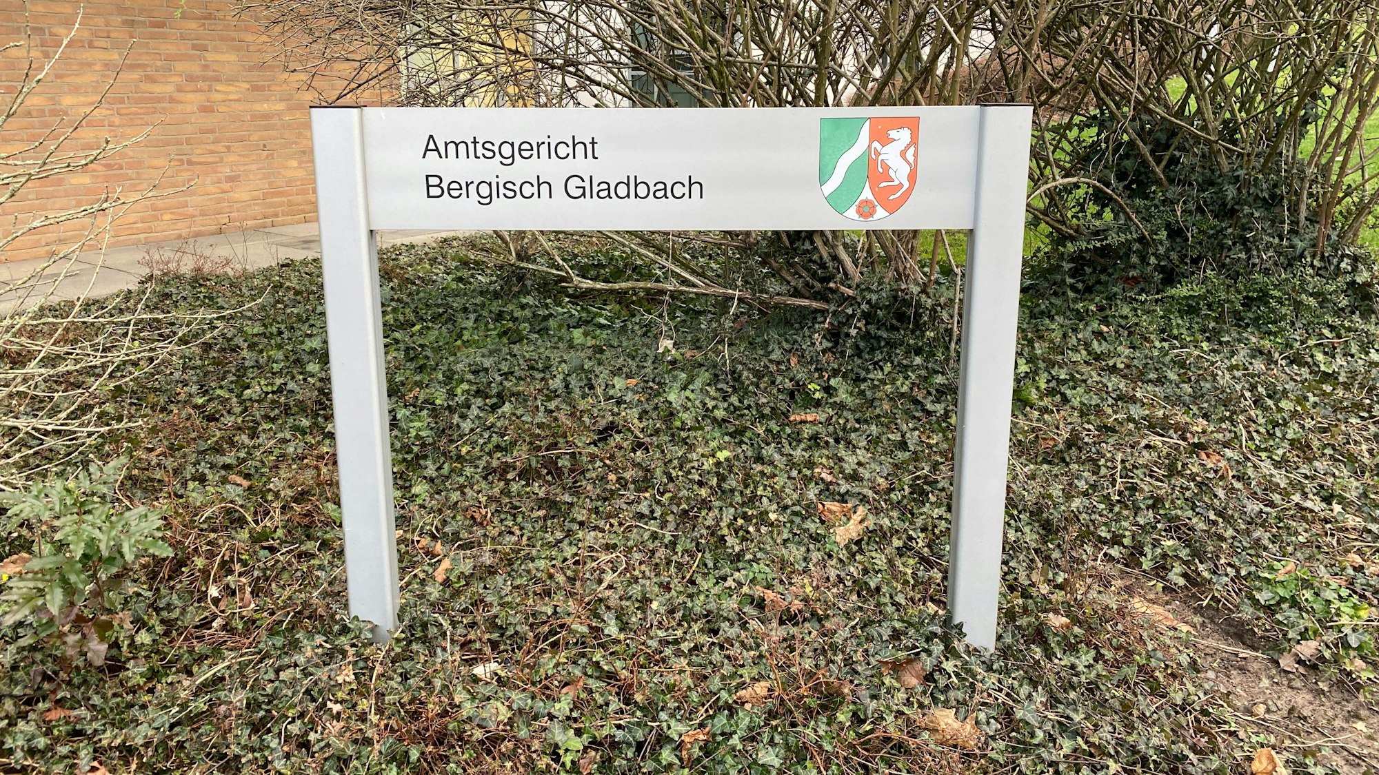 Vor dem Amtsgericht steht ein Schild mit der Aufschrift Amtsgericht Bergisch Gladbach.