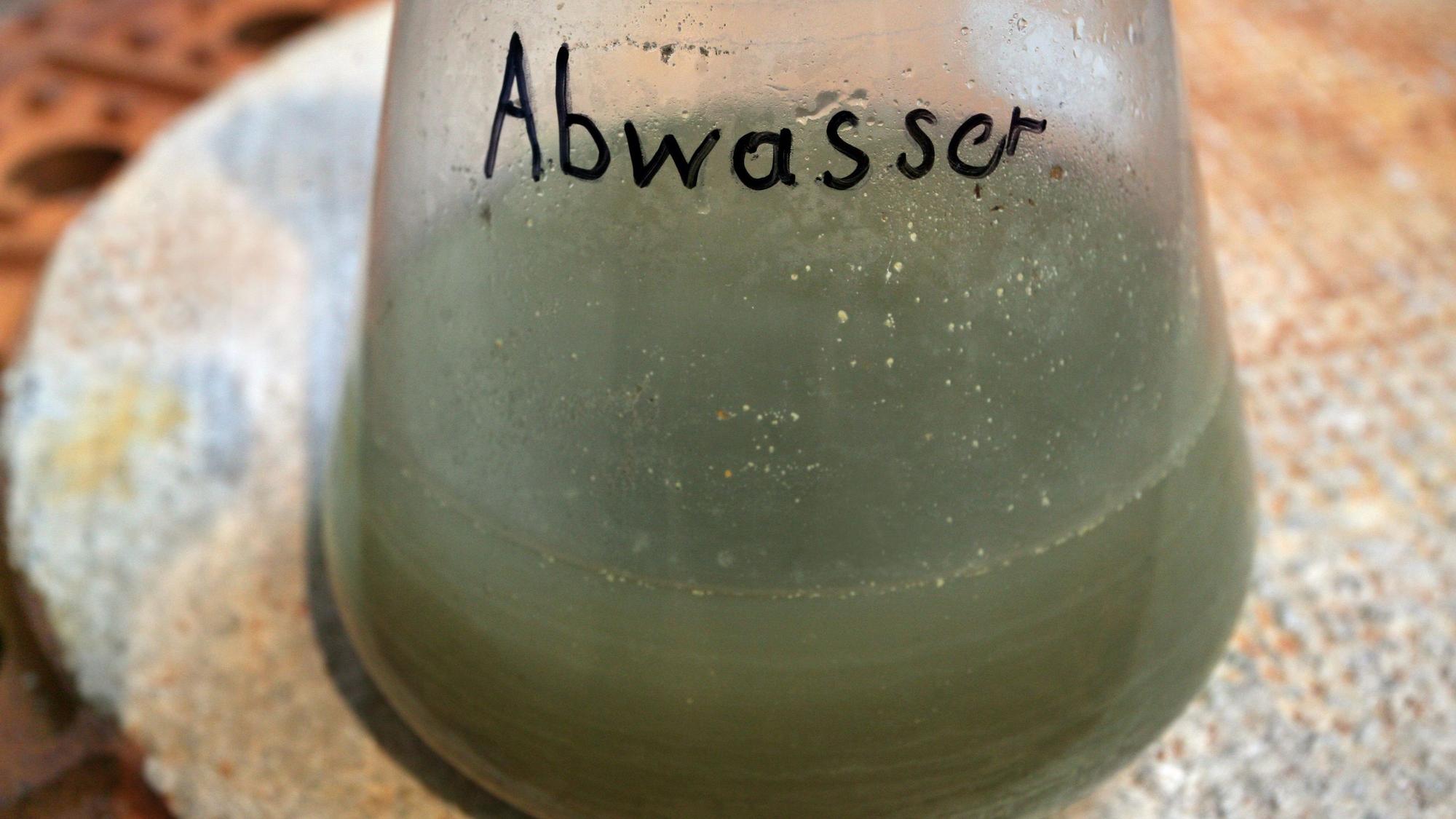 Eine Abwasser-Probe in einem durchsichtigen Behälter ist zu sehen.