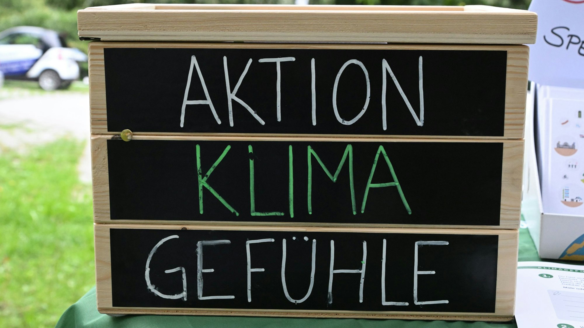 Ein Holzkasten mit der Aufschrift auf schwarzem Grund: „Aktion, Klima, Gefühle“