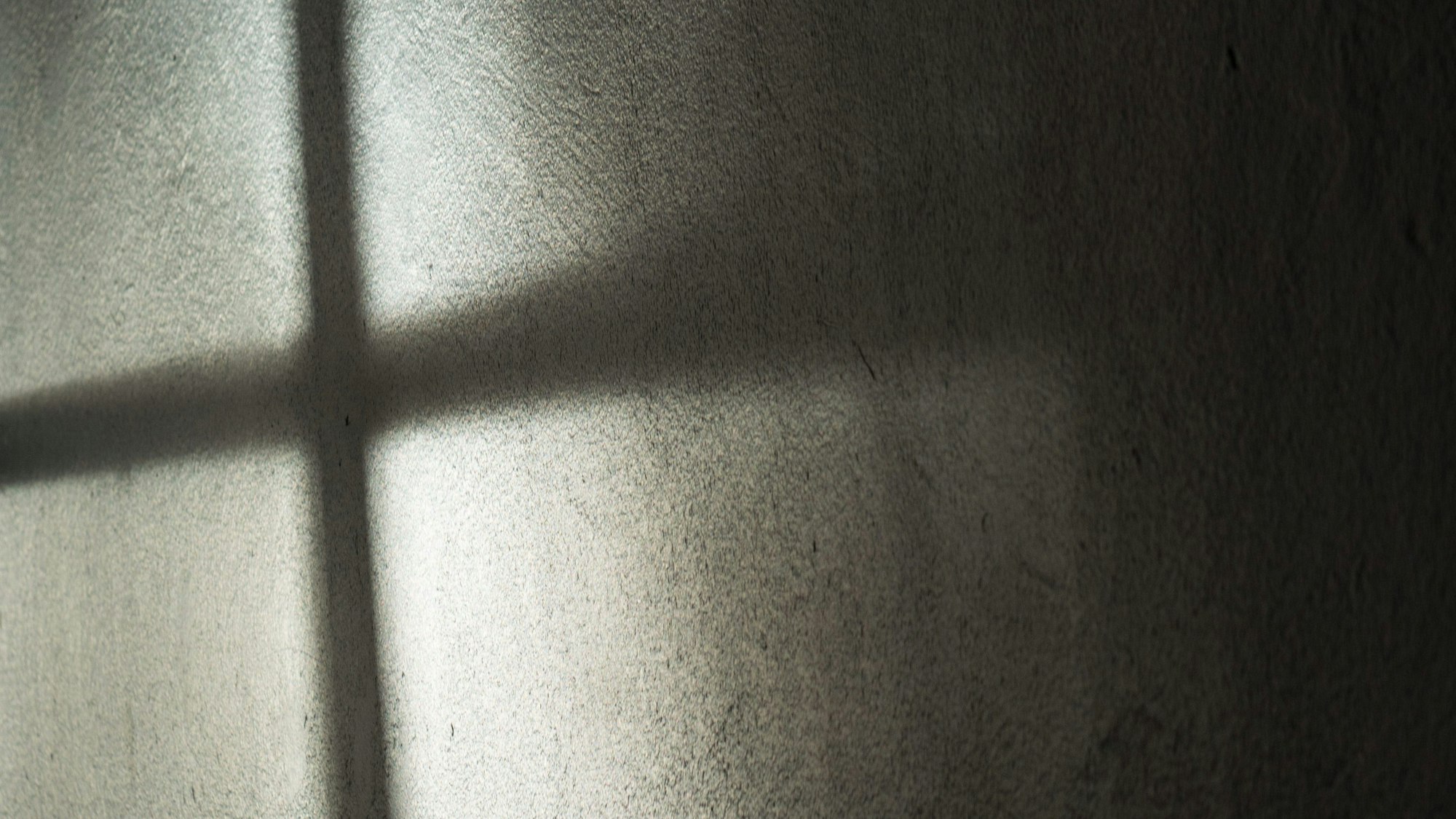 Ein Fenster wirft seinen Schatten auf die Wand. Es entsteht ein dunkles Kreuz. (Symbolbild)