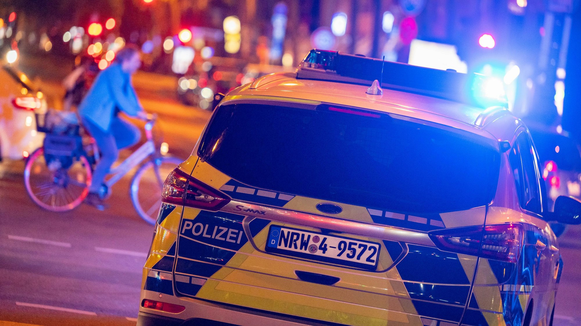 Ein Streifenwagen fährt im Dunkeln mit eingeschaltetem Blaulicht.
