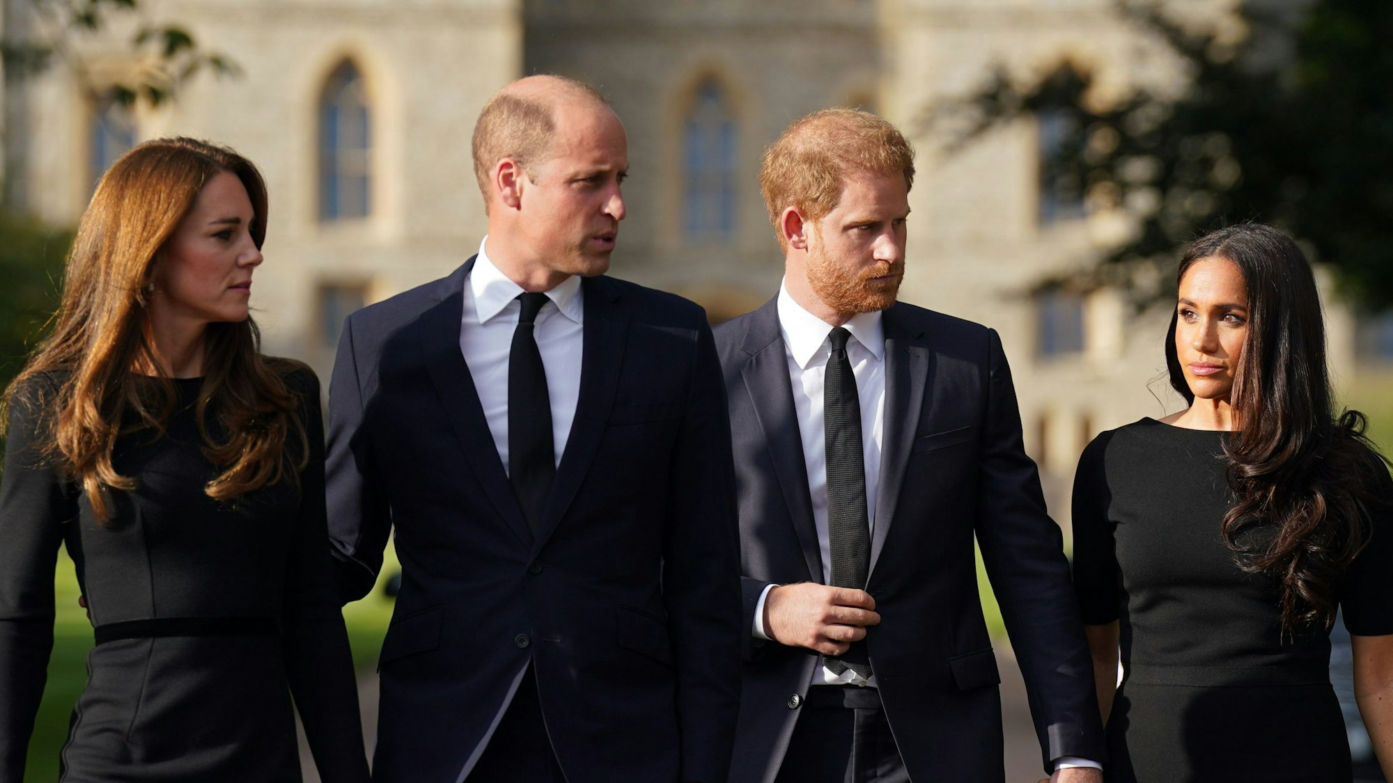 Kate, Prinzessin von Wales, William, Prinz von Wales, Prinz Harry, Herzog von Sussex, und seine Frau Meghan, Herzogin von Sussex, laufen vor dem Schloss Windsor einen Weg entlang.