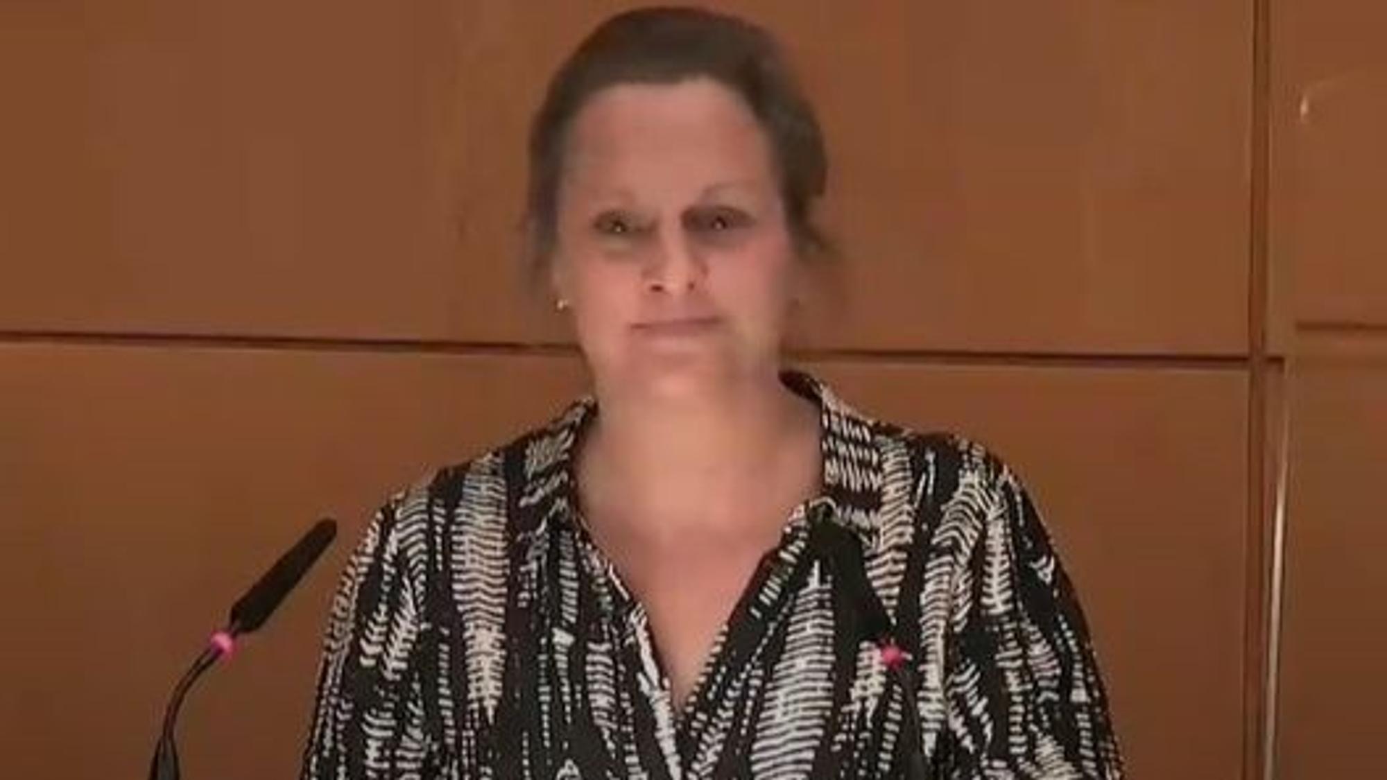 In dieser Szene klebt sich Ratsmitglied Nicole Gabrysch (Klimafreunde) mit ihrer linken Hand am Rednerpult des Ratssaals fest.