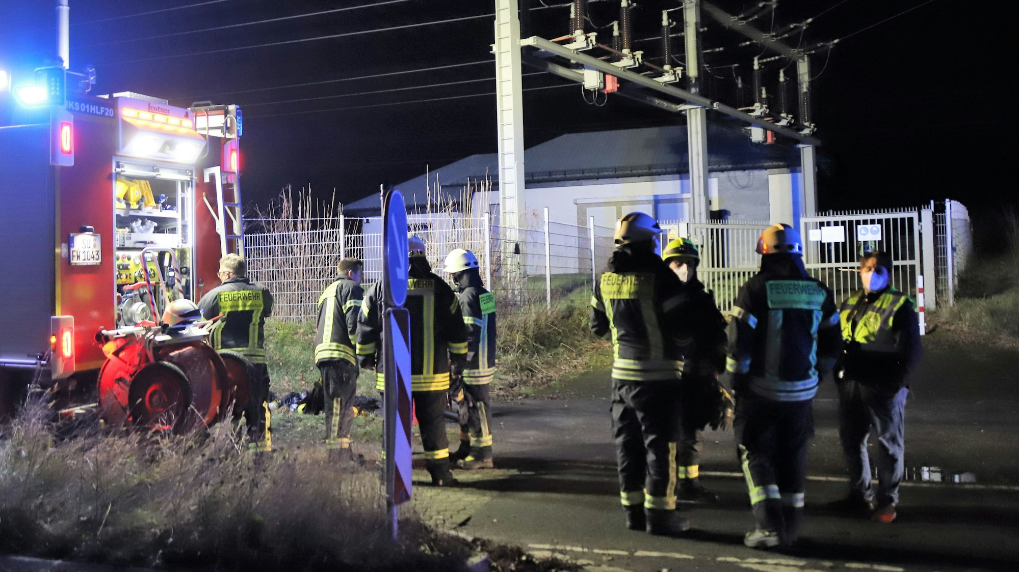 Feuerwehrleute stehen nachts an einem Umspannwerk.