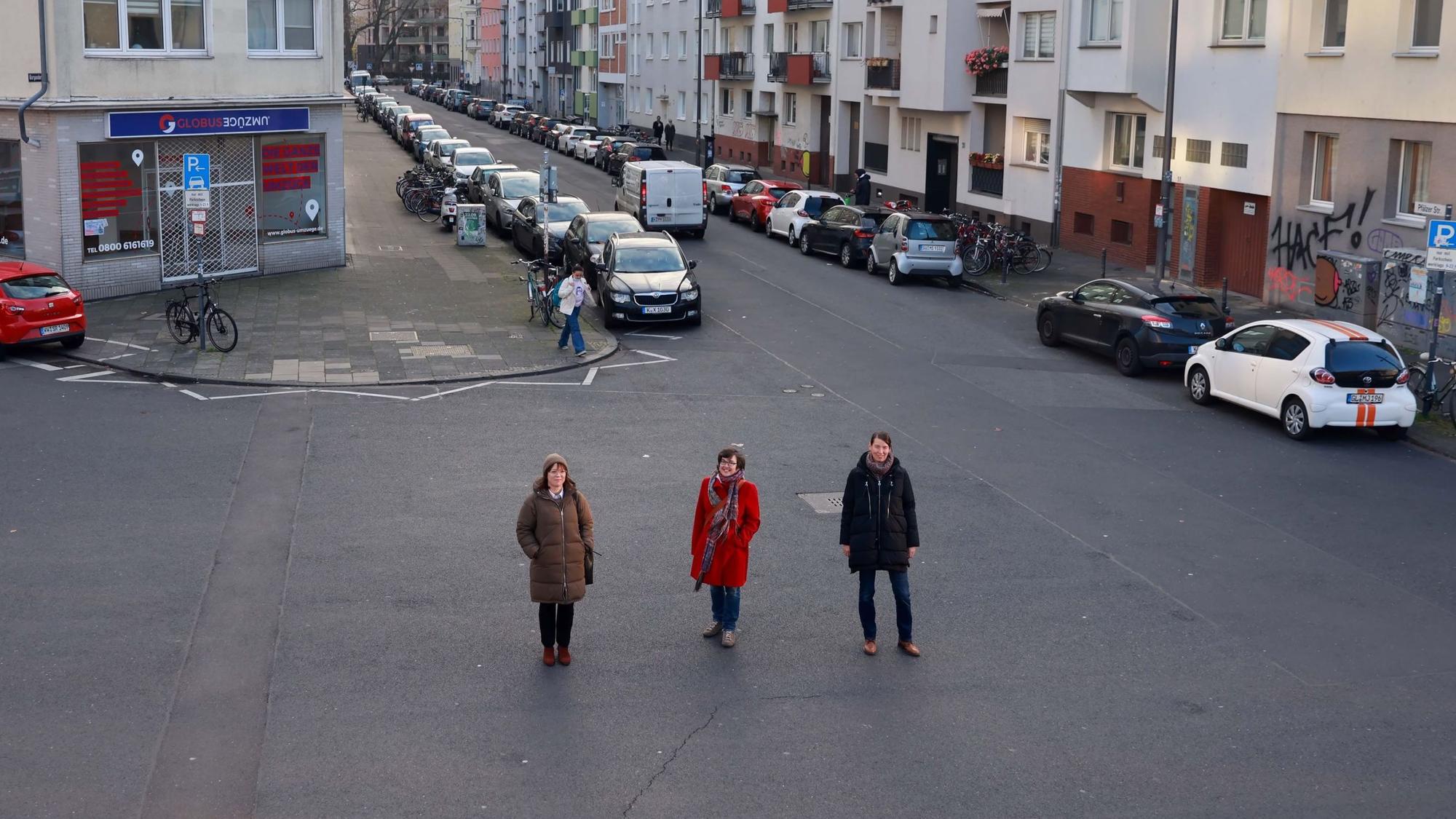 Auf ungenutztem Asphalt stehen Vera Witteck, Sybille Fraquelli und Clara Walther (v.l.) von der IG Winzerveedel.