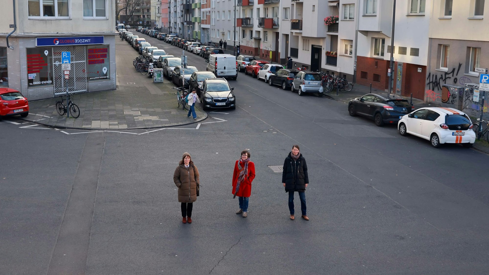 Auf ungenutztem Asphalt stehen Vera Witteck, Sybille Fraquelli und Clara Walther (v.l.) von der IG Winzerveedel.