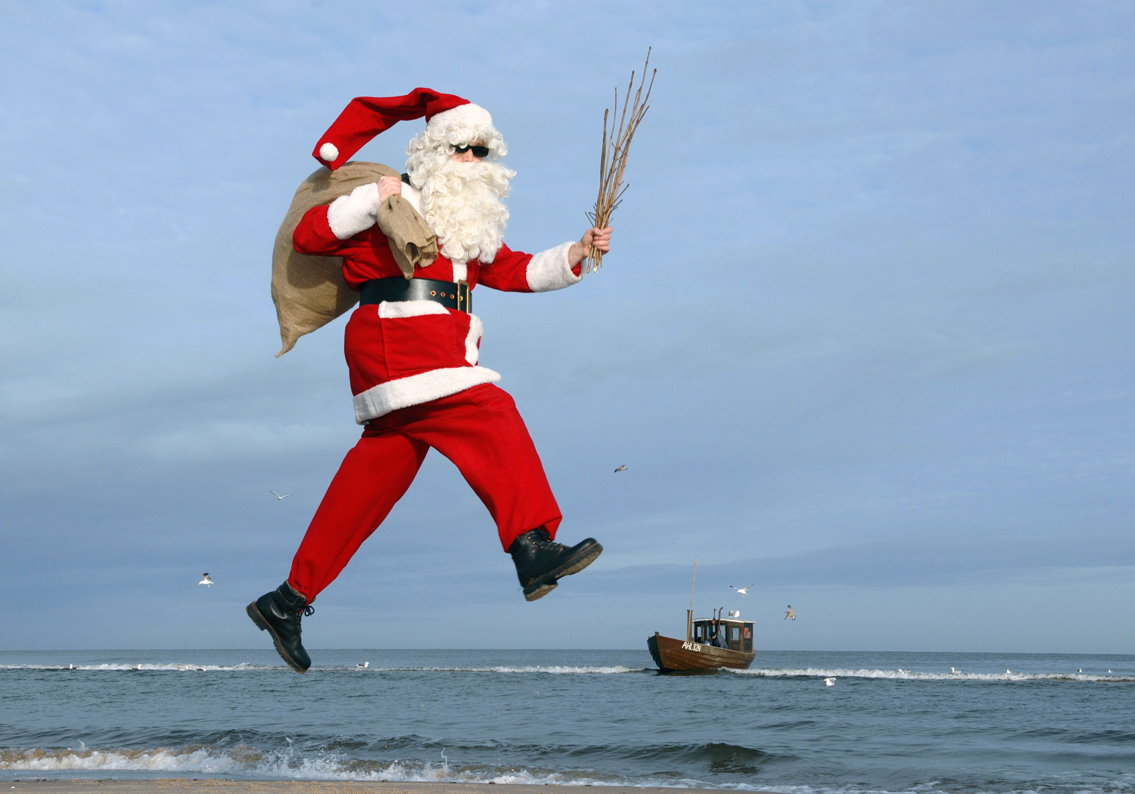Am Strand von Ahlbeck auf der Insel Usedom springt ein als Weihnachtsmann verkleideter Mann.