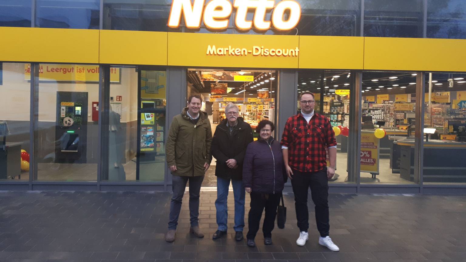 Drei Männer und eine Frau stehen vor dem Eingang des Netto-Supermarktes in Bilderstöckchen