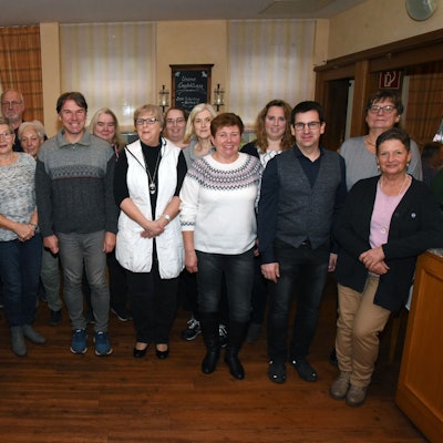 Eine mittelgroße Gruppe an langjährigen Zustellern der Zeitung stehen im Hotel Stremme in der Becke in Gummersbach. Sie lächeln in die Kamera.