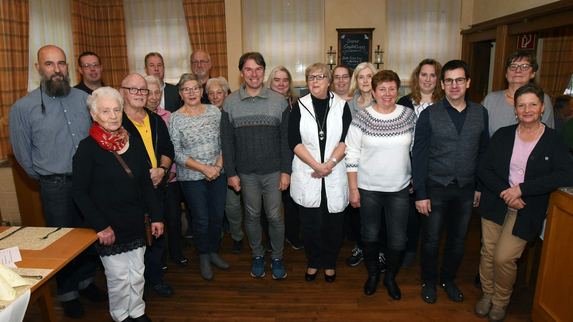Eine mittelgroße Gruppe an langjährigen Zustellern der Zeitung stehen im Hotel Stremme in der Becke in Gummersbach. Sie lächeln in die Kamera.