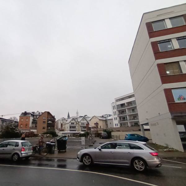 Zwei Autos fahren auf der Straße an dem Baugrundstück in der Sieburger Innenstadt an der Wilhelmstraße vorbei. Das Grundstück liegt zwischen Wohn- und Bürogebäuden und dem Gymnasium Alleestraße.